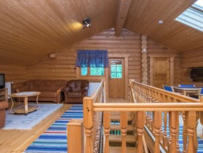 L’intérieur d’une cabane en rondins, avec un escalier en bois, un canapé en cuir et une petite table.