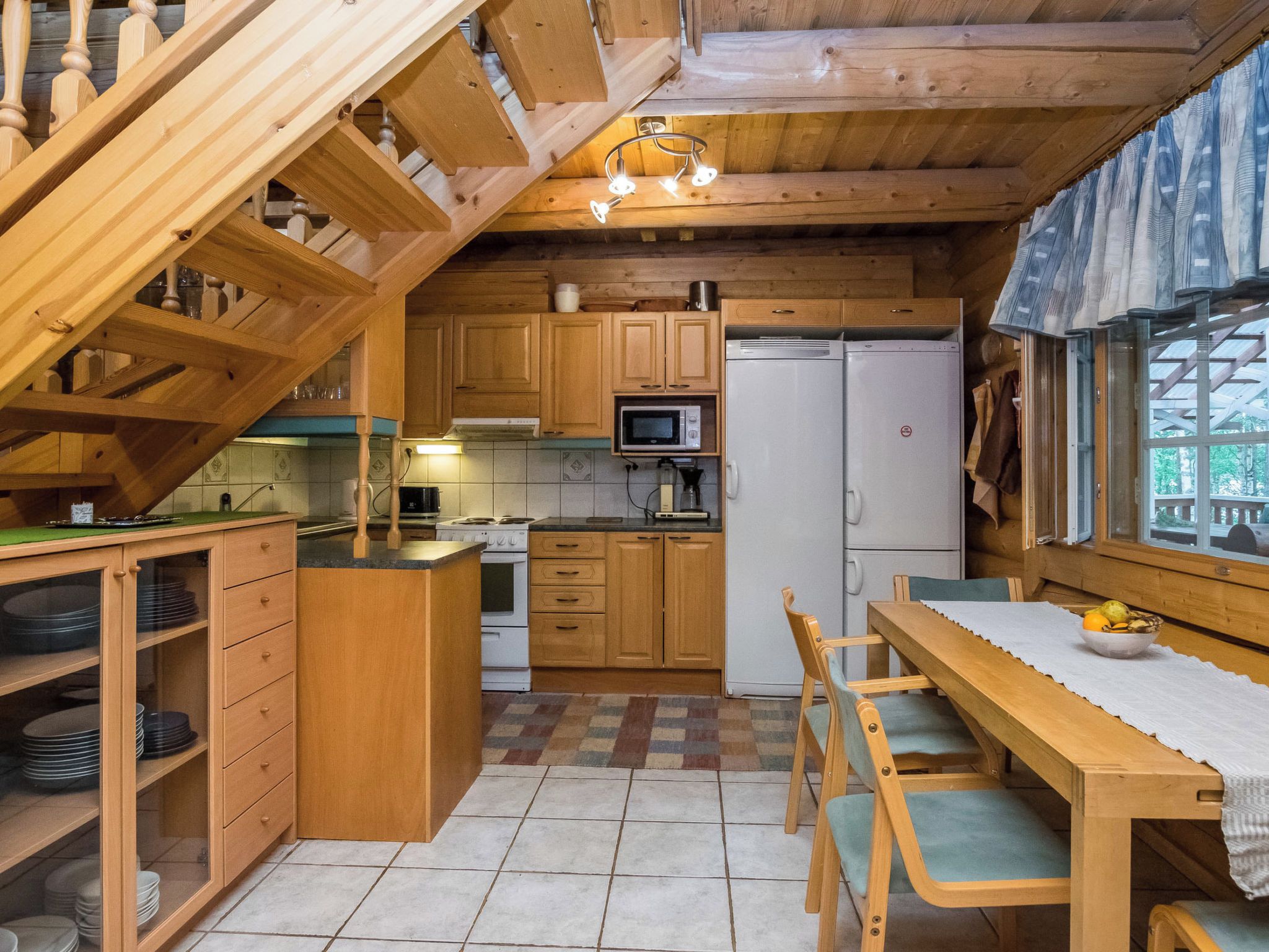 Une cuisine compacte dotée de meubles en bois, d’un four à micro-ondes, d’un réfrigérateur et d’un coin repas avec une table et des chaises.