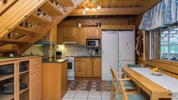 Une cuisine compacte dotée de meubles en bois, d’un four à micro-ondes, d’un réfrigérateur et d’un coin repas avec une table et des chaises.