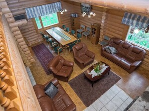 A log cabin interior with a dining area, sofas, and a fireplace.