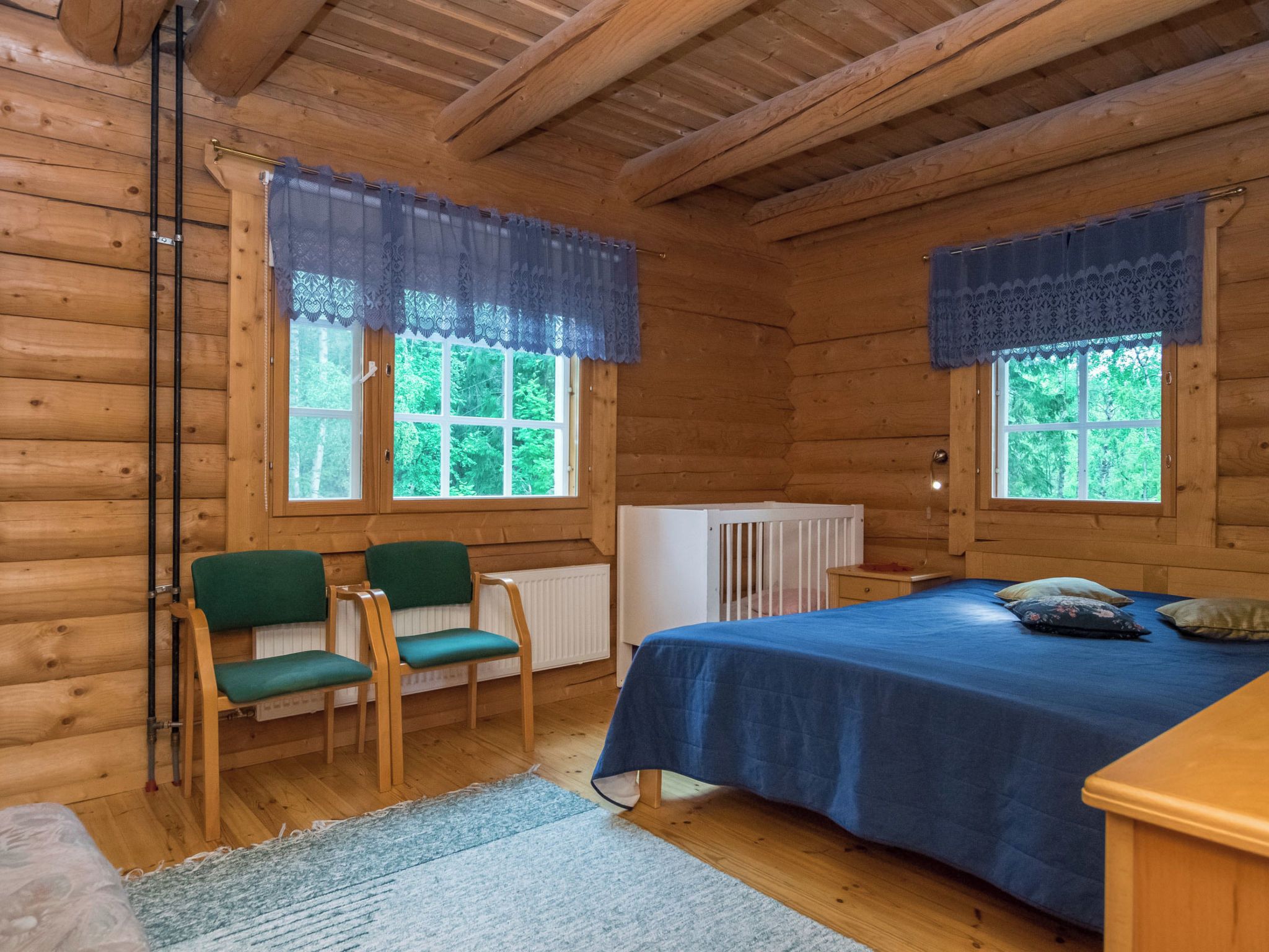 Une chambre de style rustique avec deux fenêtres, un lit, deux chaises et un radiateur.