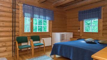 Une chambre de style rustique avec deux fenêtres, un lit, deux chaises et un radiateur.