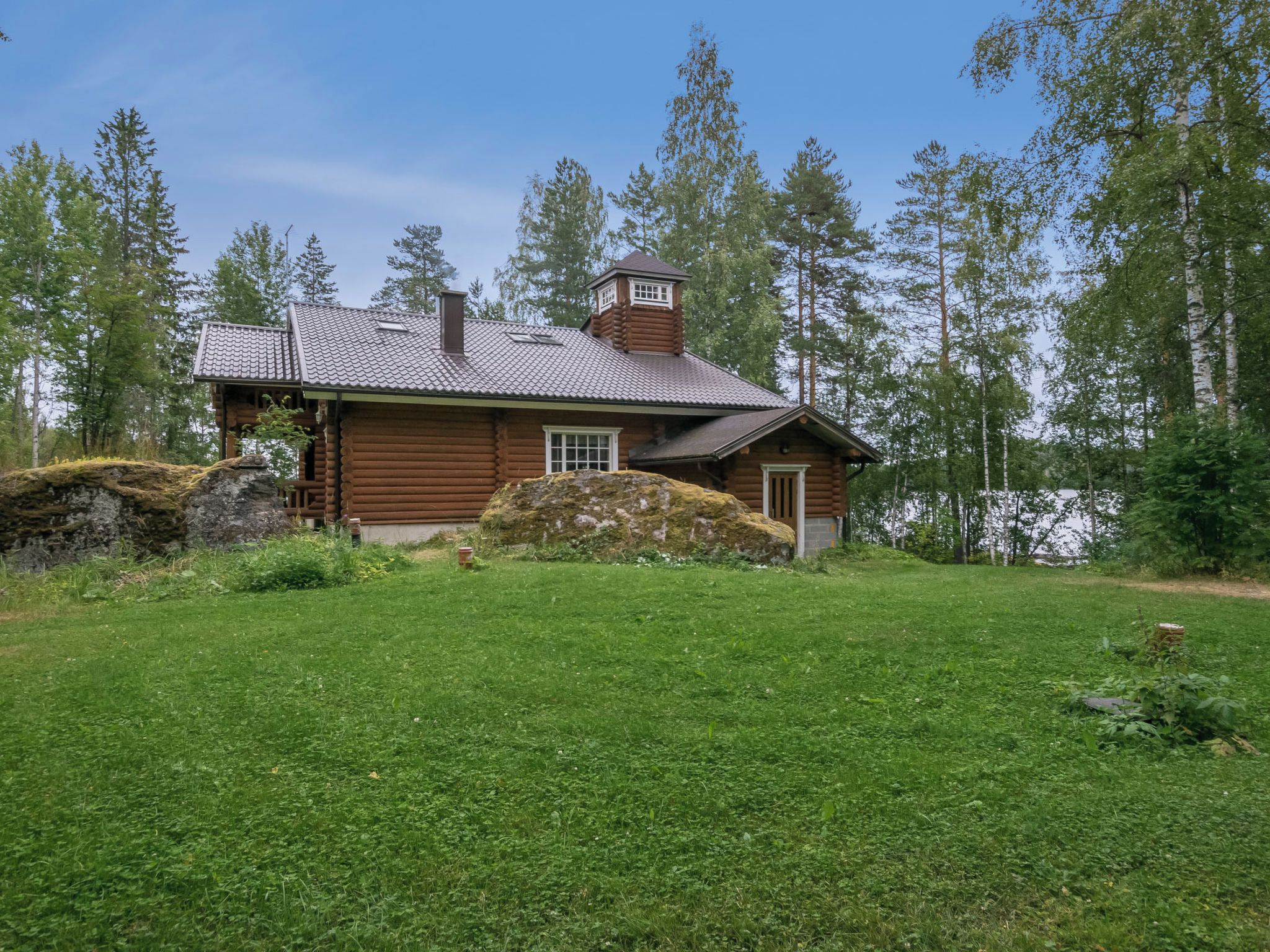 A log cabin with a sloped roof, a chimney, and a small porch.