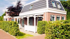 Une maison moderne dotée d’un porche abrité, de panneaux solaires et d’une façade en briques.