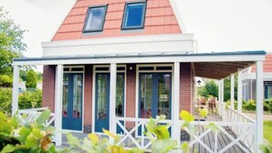 Une petite maison en briques avec un toit rouge et une véranda.