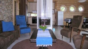Una sala de estar moderna con chimenea, sofás azules y un comedor con mesa y sillas.