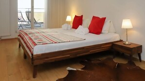 Une chambre à coucher avec un lit en bois, deux lampes de chevet, une couvre-lit rouge et blanche et un tapis en cuir.