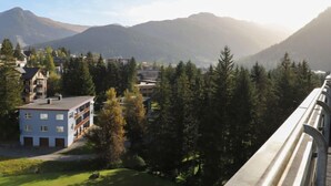 Un quartier résidentiel avec un immeuble bleu, entouré d’arbres et avec des montagnes en arrière-plan.