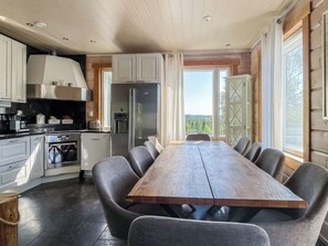 A modern kitchen with a central island, a dining table with chairs, and a view of the outdoors.