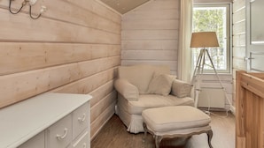 Een gezellig kamer in een blokhut met houten inrichting, een bank, een klein tafeltje en een lamp.