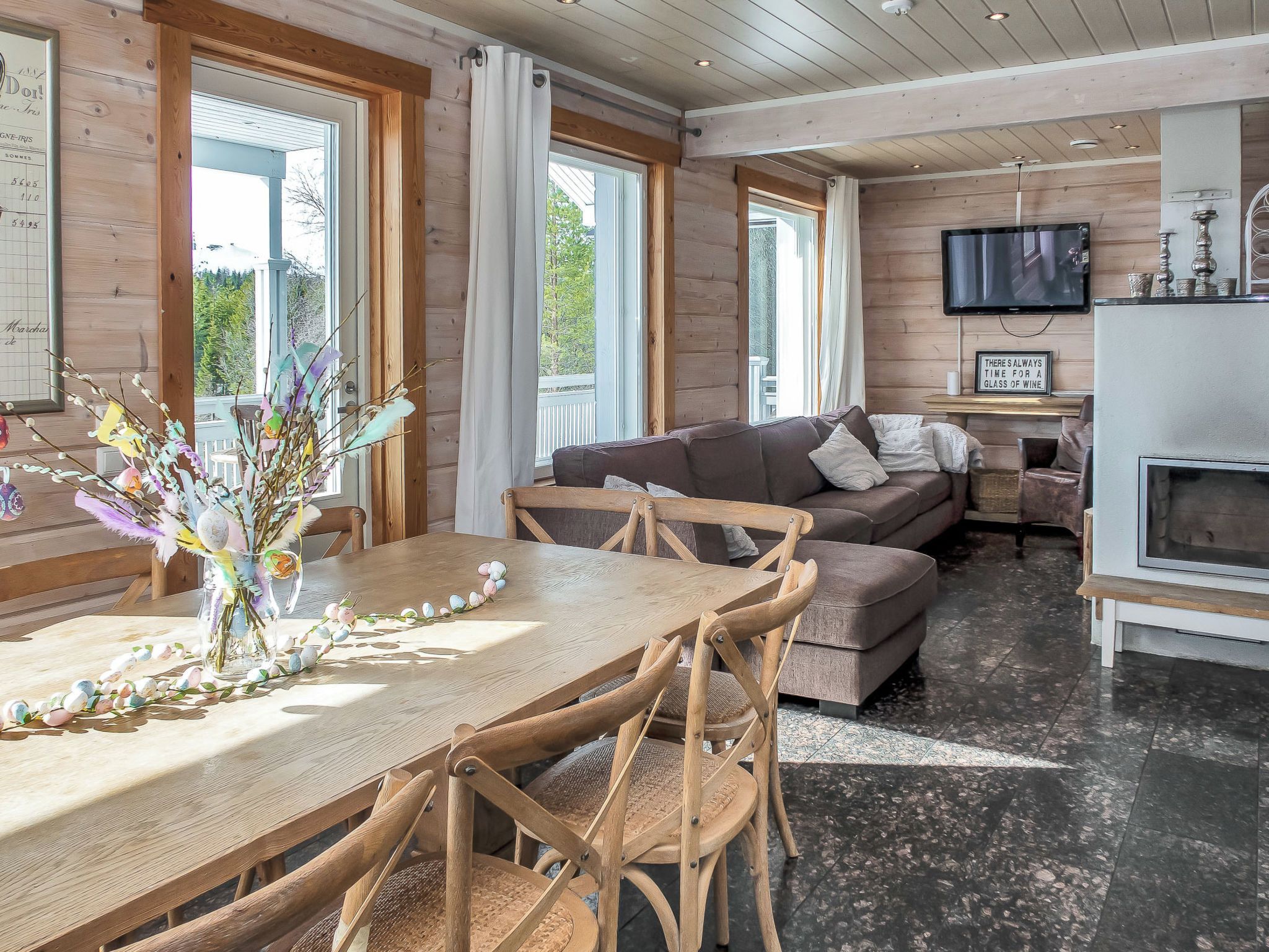 A cozy living room with a wooden table, chairs, a sofa, and a television.