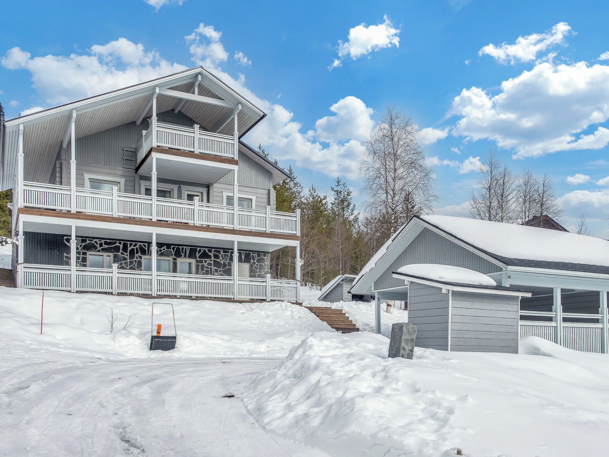 A multi-story building with a balcony, a covered porch, and a garage.