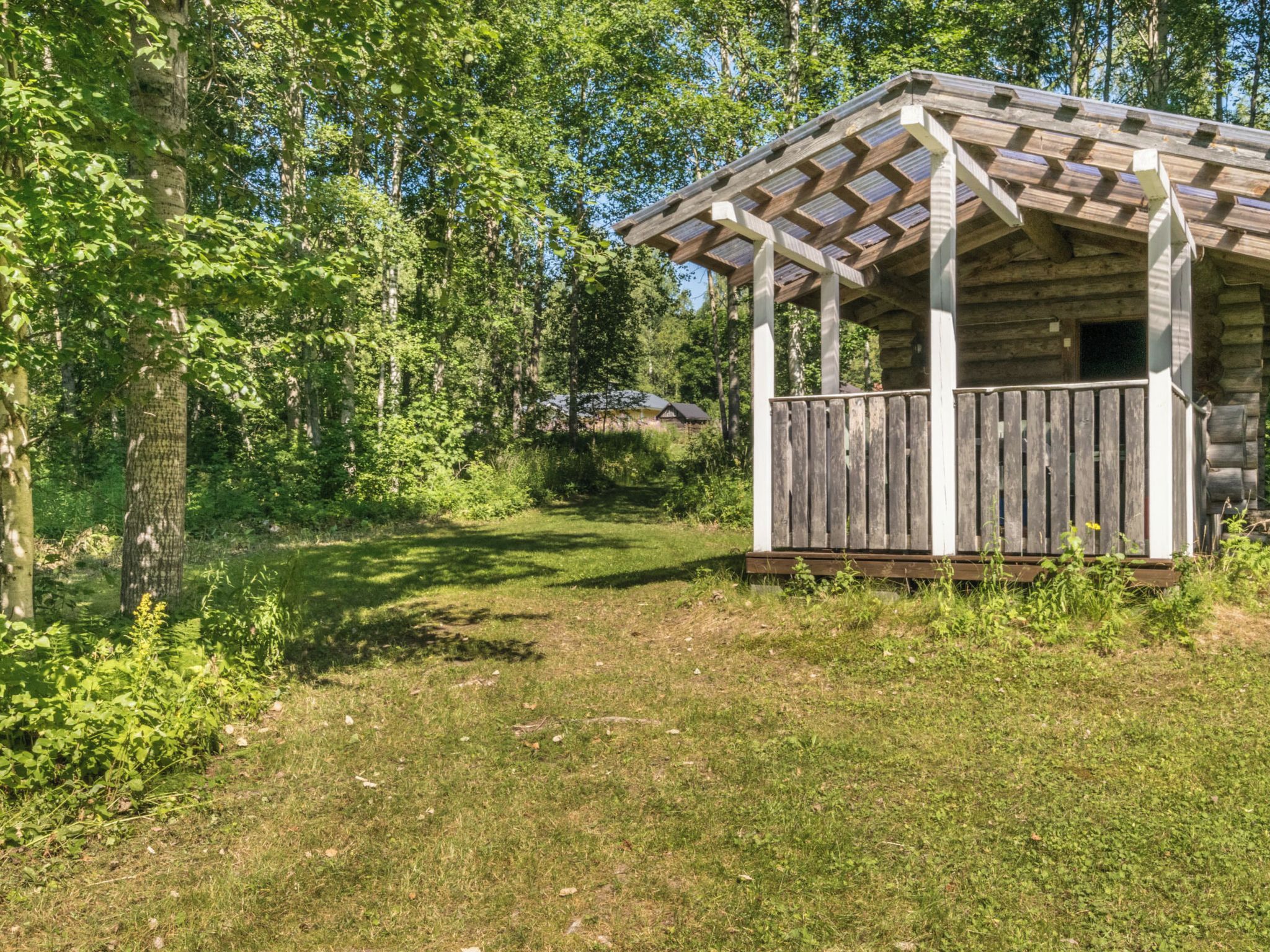 Ein rustikales Blockhaus mit einer Holzterrasse, umgeben von dichtem Wald.