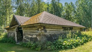 Eine rustikale Blockhütte mit Stein Fundament, einer Holztür und einer kleinen Veranda.