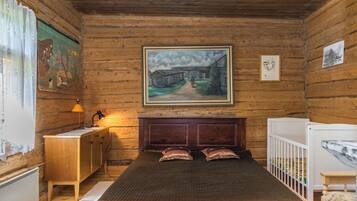 Una habitación de madera con una cama, un escritorio, un radiador y un cuadro en la pared.