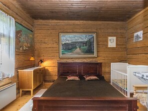 Une pièce en bois avec un lit, un bureau, un radiateur et un tableau accroché au mur.