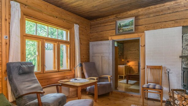 Ein gemütliches Blockhaus-Interieur mit Holzwänden, Kamin und Essbereich.