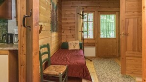 Ein Holzhütten-Interieur mit Bett, Stuhl, Fenster und Tür.