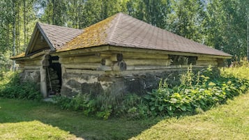 Ein rustikales Blockhaus mit geneigtem Dach, Schornstein und kleiner Veranda.
