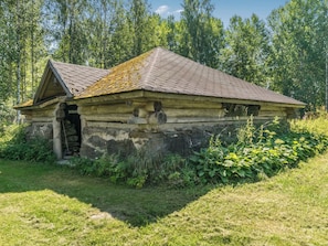 Ein rustikales Blockhaus mit geneigtem Dach, Schornstein und kleiner Veranda.
