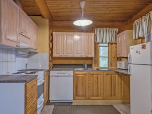 A kitchen with wooden cabinets, a stove, a dishwasher, and a refrigerator.