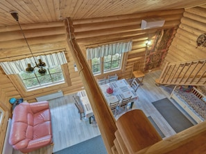 A cabin interior with a dining area, a sofa, and a staircase.