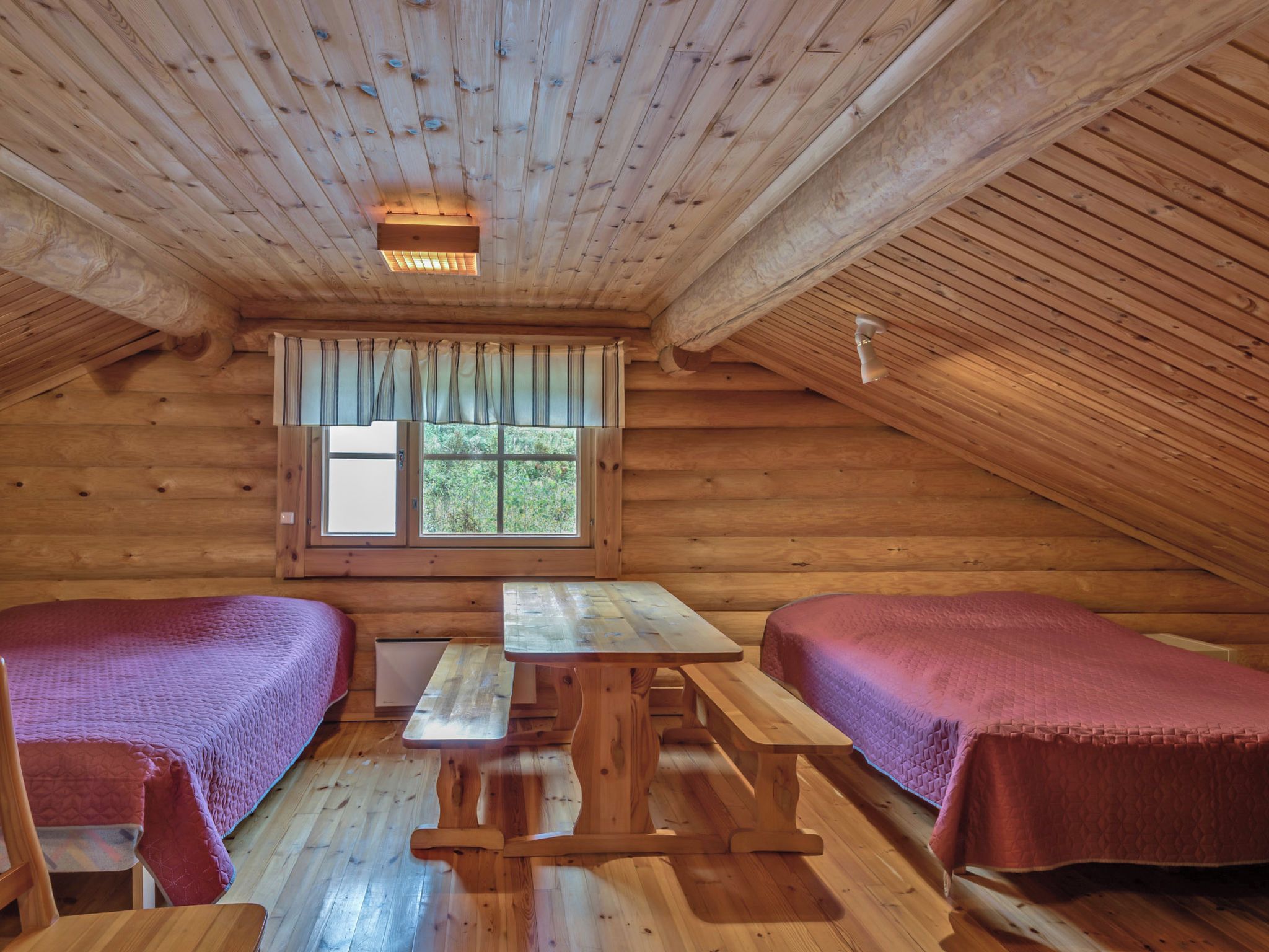 Eine Hütte mit zwei Betten, einem Tisch und einem Fenster.