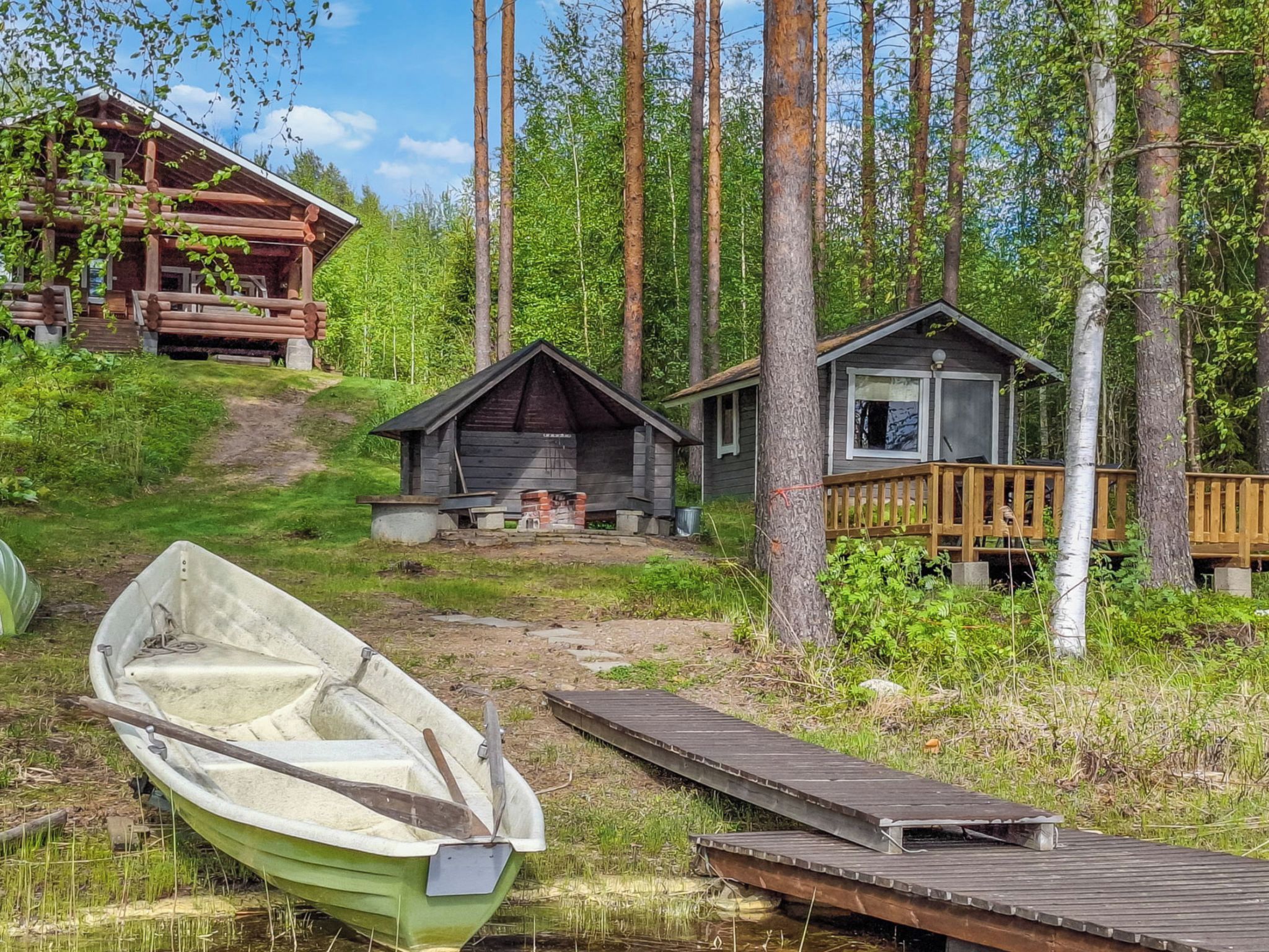 Une cabane avec un quai et un bateau, entourée de forêt.