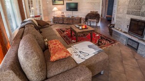 A cozy living room with a large sectional sofa, a fireplace, and a television on the wall. - Ylläs siesta by Interhome (Ylläsjärvi)