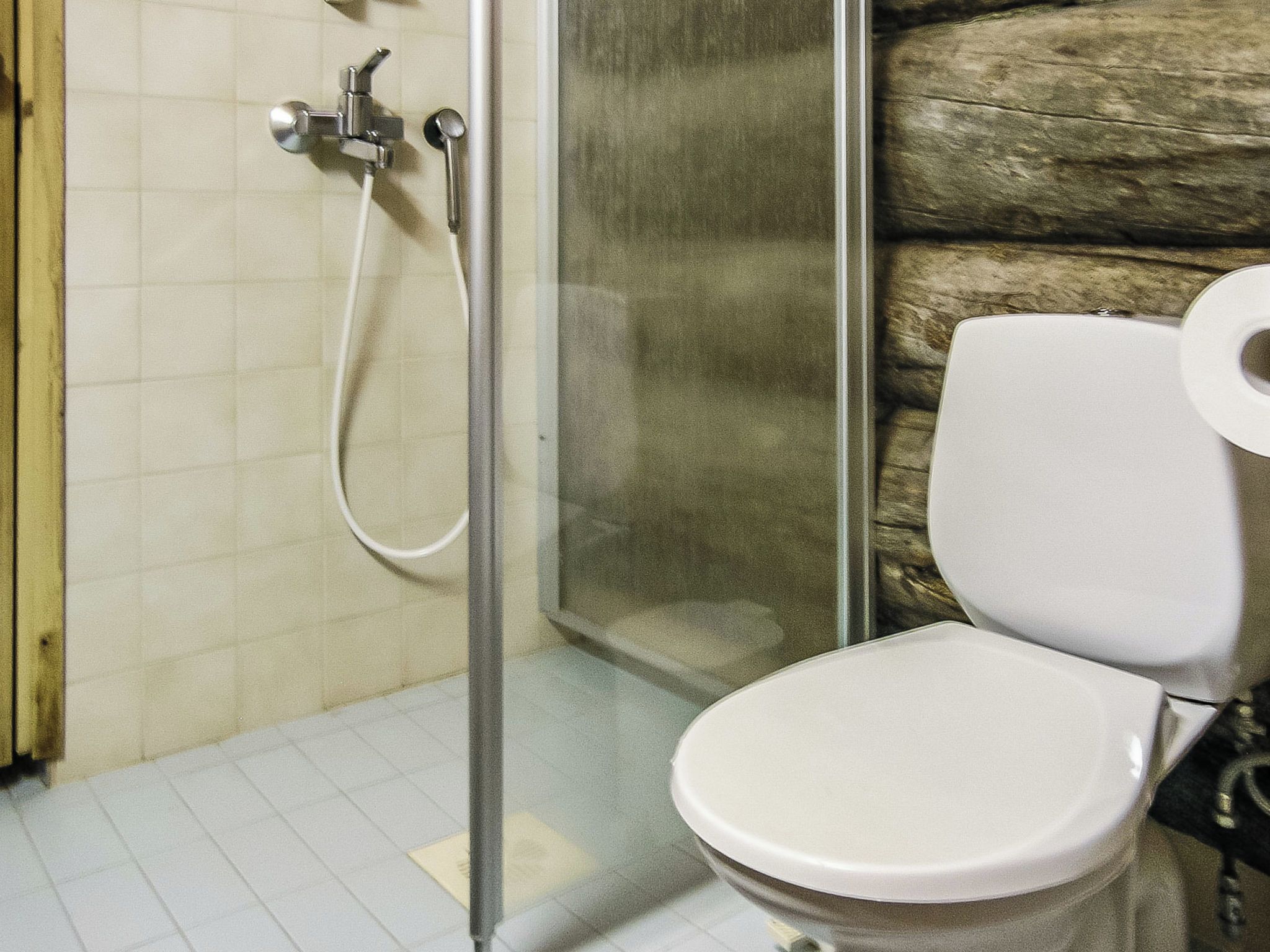 Une salle de bain comprenant des toilettes, un espace douche et un sol carrelé.