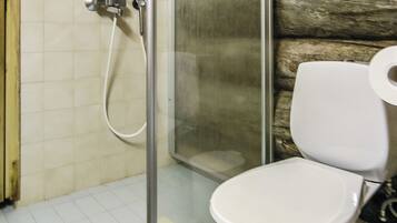 Une salle de bain comprenant des toilettes, un espace douche et un sol carrelé.