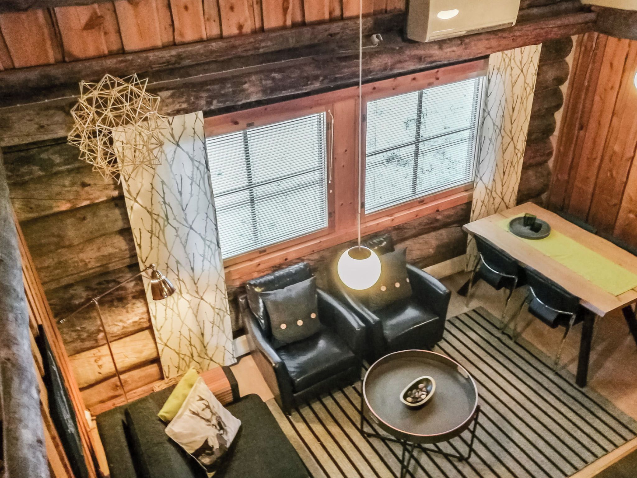 Een gezellig chaletinterieur met een bank, een tafel en een lamp.