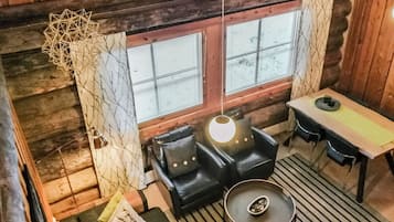 Een gezellig chaletinterieur met een bank, een tafel en een lamp.