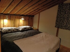 A bedroom with a bed, two bedside lamps, and a patterned wall hanging.