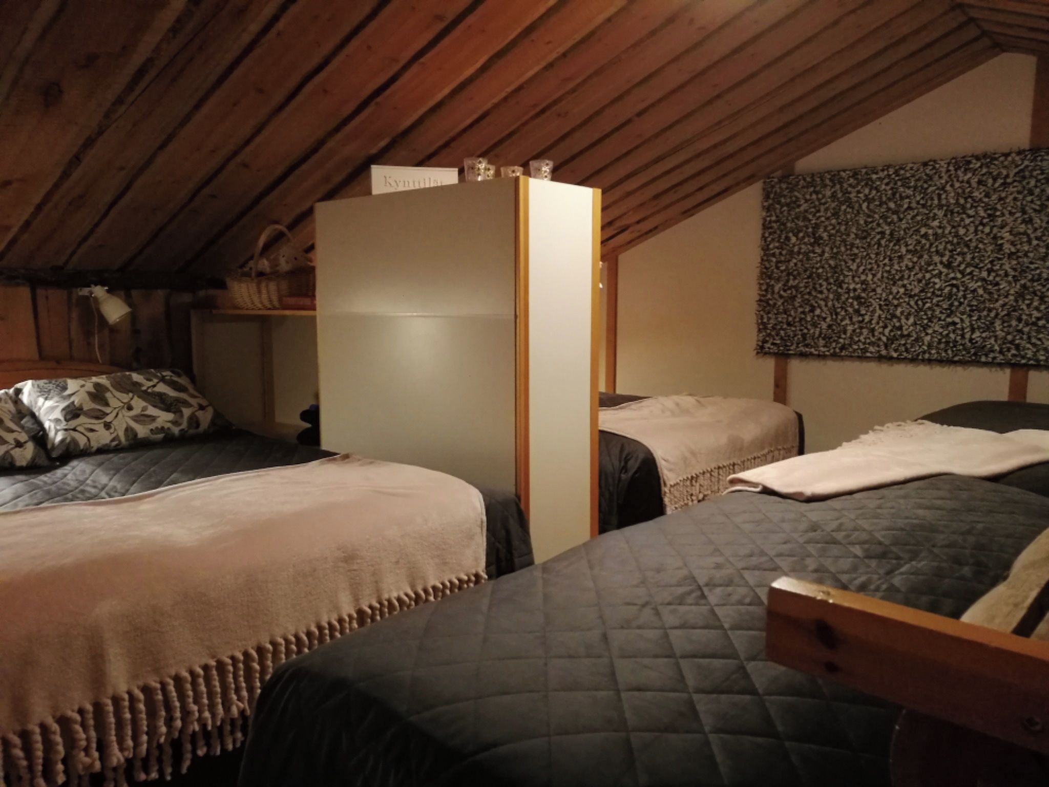 A room with two beds, a wooden wardrobe, and a patterned wall.