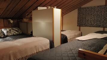 A room with two beds, a wooden wardrobe, and a patterned wall.