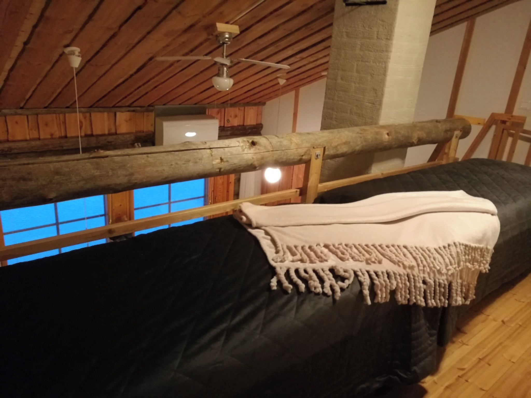 Een kamer met een bed, een houten plafond en een raam.