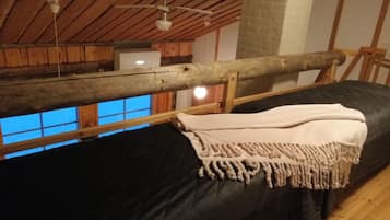 Een kamer met een bed, een houten plafond en een raam.
