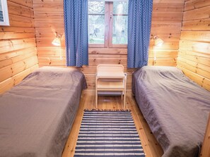 A cabin with two single beds, a small table, and a window with curtains.