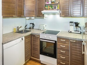 A compact kitchen with a dishwasher, stove, toaster, and coffee maker.