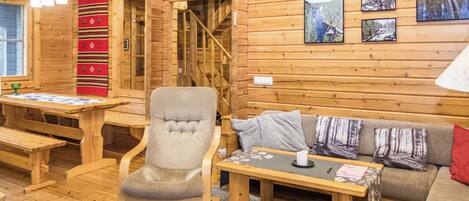 Interior acogedor de una cabaña con detalles de madera, un sofá, una silla, una mesa y una chimenea.