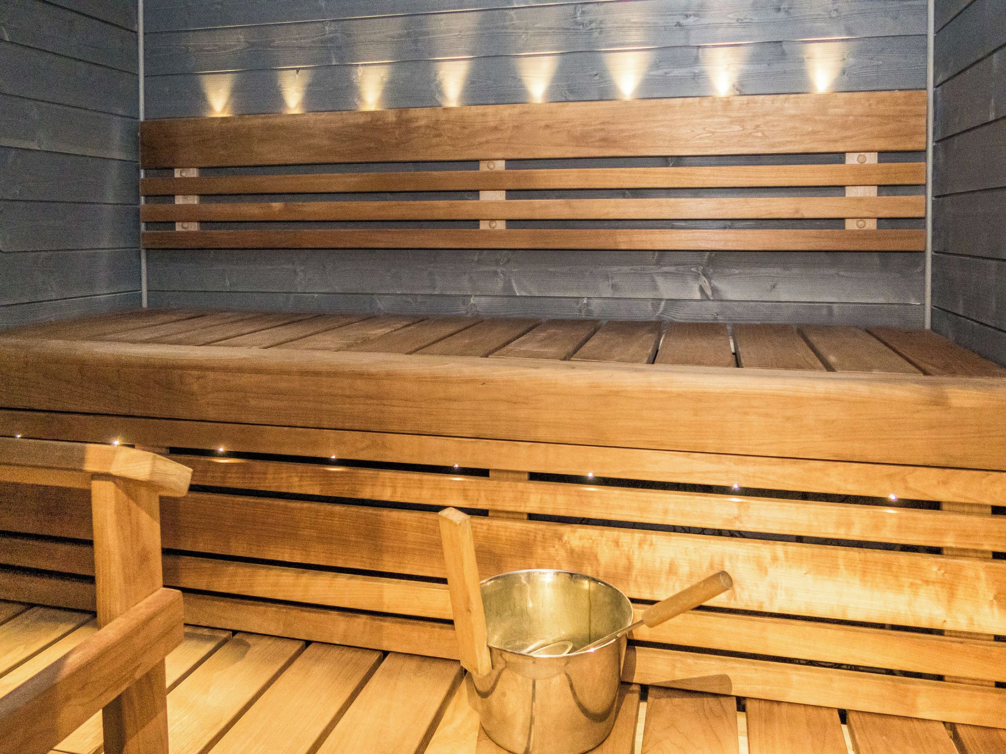 Una sauna con bancos de madera y un cubo de metal.