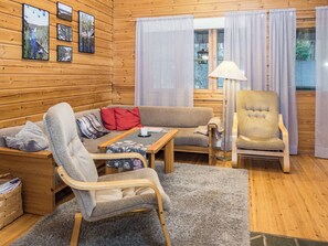 A cozy cabin interior with a sofa, chairs, a table, and a lamp.