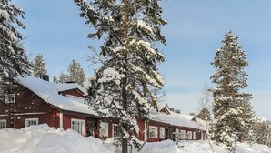 A snow-covered building with a red exterior and multiple windows, surrounded by snow-laden trees. - Soidinaukea b 20 by Interhome (Inari)