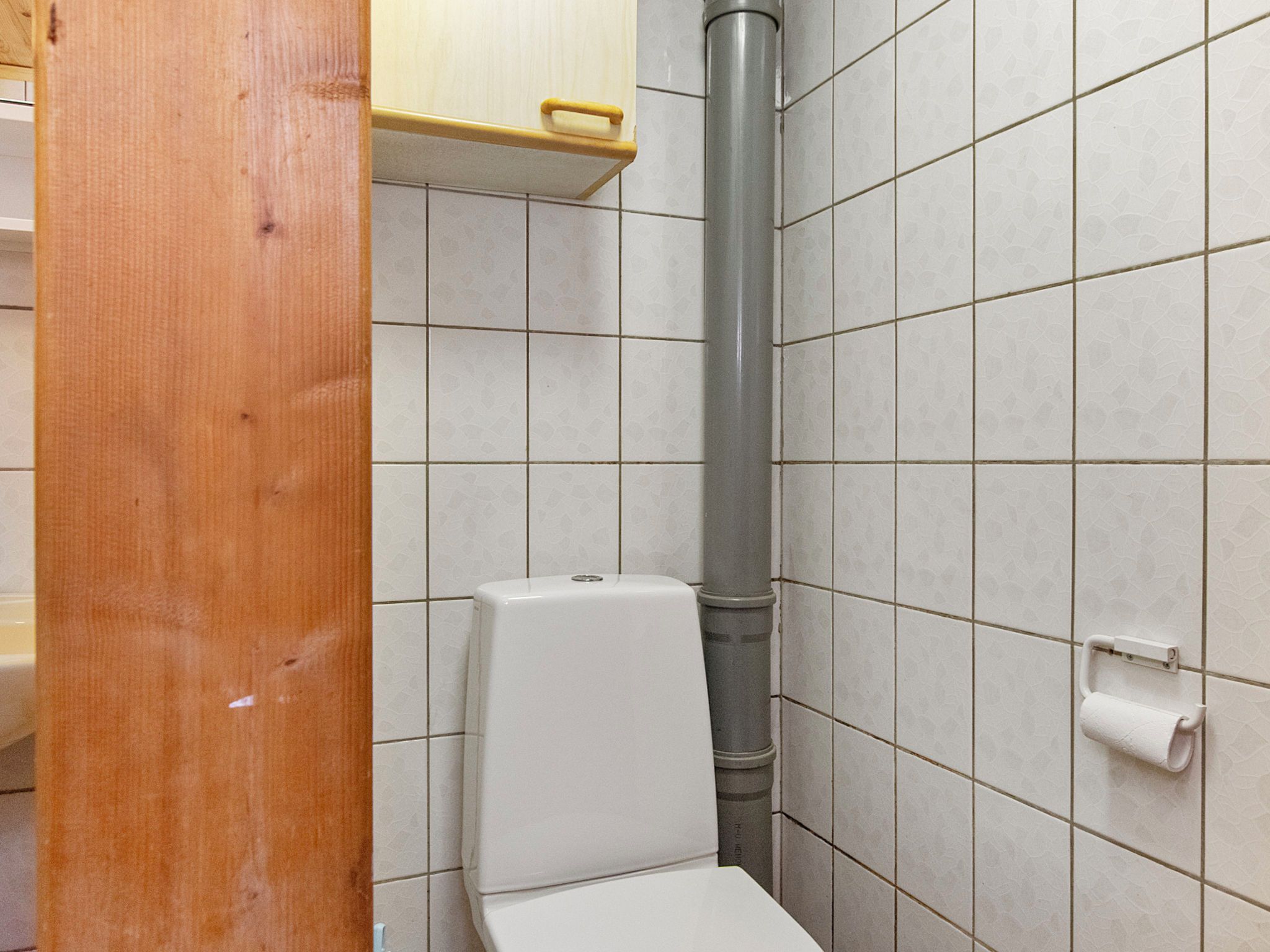 A small, tiled bathroom with a toilet, a hand dryer, and a paper towel dispenser.