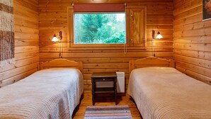Una camera tipo cabina con due letti, una finestra e un piccolo tavolo.