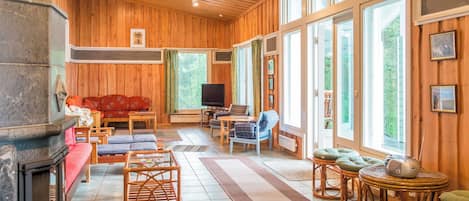 Una sala de estar acogedora con chimenea, paredes de madera y ventanas amplias.