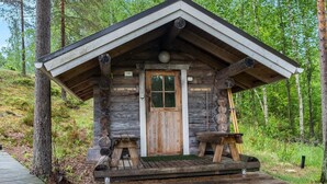 Una cabaña rústica con puerta de madera, un porche pequeño y un banco.