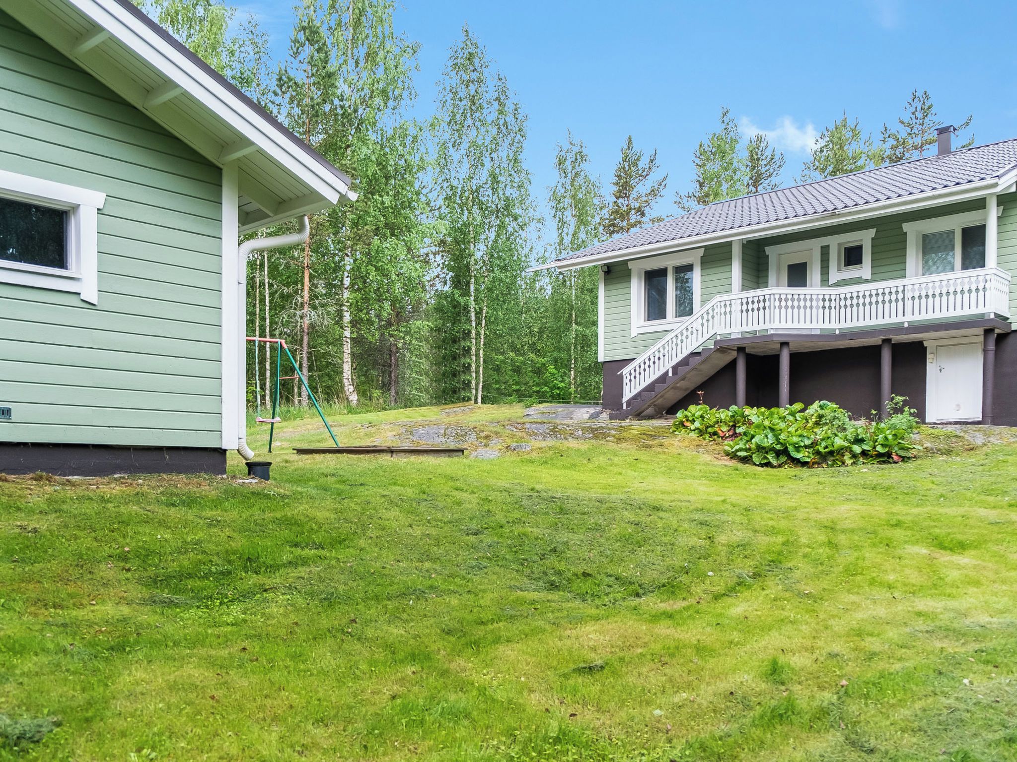 A two-story house with a front porch and a small garden area.