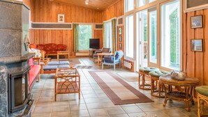Una sala de estar acogedora con paredes de madera y ventanas amplias, una chimenea y asientos cómodos.